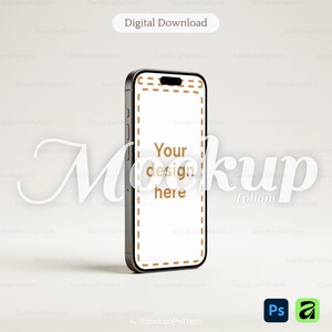 Peut inclure: Un smartphone noir servant de maquette avec un écran blanc bordé d'une ligne pointillée marron et le texte Your design here. Le haut de l'écran présente une découpe en forme de pilule. L'appareil est vu sous un léger angle sur fond clair.