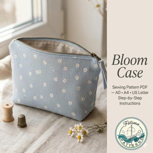 Puede incluir: Un estuche Bloom de pana azul claro con patrones de margaritas blancas, abierto para revelar un interior beige. El estuche tiene cierre de cremallera y un asa pequeña. El texto "Bloom Case" es visible.