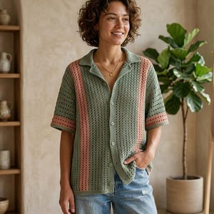 Puede incluir: Una camisa verde de ganchillo con mangas cortas y cuello. La camisa presenta rayas verticales en color rosa claro en la parte delantera. La camisa est&aacute; abotonada y se usa con vaqueros azules.