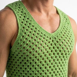 Op de afbeelding: Een groene, open geweven gehaakte tanktop met een V-hals. De mouwloze top is effen lichtgroen van kleur en lijkt handgemaakt. Het haakpatroon creëert een rasterachtig ontwerp.