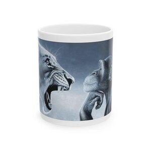 May include: White ceramic mug featuring a detailed illustration of a roaring lion and a thoughtful chimpanzee. The artwork is in shades of gray and white against a blue background. The mug is a standard size for coffee or tea.