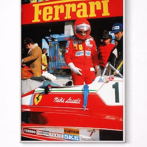 Peut inclure: Impression encadrée d'une voiture de course de Formule 1 et d'un pilote vintage. La voiture rouge porte le nom "Niki Lauda" et le logo Ferrari. Le pilote porte une combinaison et un casque de course rouges. Le mot "Ferrari" est affiché en grandes lettres jaunes.