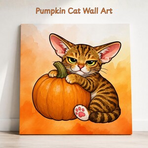 Könnte beinhalten: Ein quadratischer Wandkunstdruck, der eine braune getigerte Katze mit großen Ohren und gelben Augen zeigt, die einen runden orangefarbenen Kürbis umarmt. Der Text Pumpkin Cat Wall Art steht oben. Der Hintergrund ist ein weicher, orangefarbener Aquarellverlauf.
