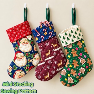May include: Three quilted Christmas stockings with hanging loops. The left stocking features Santa Claus faces on blue fabric with a red cuff. The centre stocking has reindeer and snowflakes on maroon fabric with a candy cane cuff. The right stocking displays gingerbread men and houses on green fabric with a tree-patterned cuff.