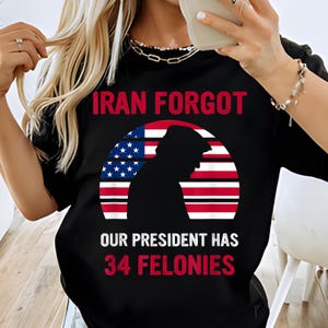 May include: Black t-shirt with the text "IRAN FORGOT" in red. Below is a graphic of a silhouette of a person in front of an American flag design. The text "OUR PRESIDENT HAS 34 FELONIES" is below the graphic.
