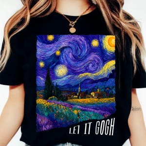 Op de afbeelding: Zwart T-shirt met een levendige print van Van Goghs schilderij "De Sterrennacht". Het ontwerp toont wervelende blauwen, gelen en paarsen, met de tekst "LET IT GOGH" in het wit. Een draagbaar kunstwerk.
