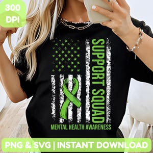 May include: Black t-shirt featuring a distressed American flag design with a green ribbon and the words "SUPPORT SQUAD" and "MENTAL HEALTH AWARENESS." The design includes green stars and white stripes.