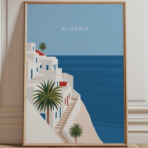以下が含まれることがあります： アルジェリアの海岸風景を描いた縦型の額入りアートプリント。白い建物、赤い屋根、青いドアが特徴です。階段が砂浜へと続き、深い青色の海と明るい青空が広がっています。中央上部には「ALGERIA」という文字が記されています。