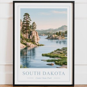 Peut inclure: Une affiche encadrée représentant un paysage du parc d'État de Custer dans le Dakota du Sud. L'image montre un lac calme entouré de falaises rocheuses, de pins et de rivages herbeux sous un ciel clair. Le texte indique SOUTH DAKOTA Custer State Park.