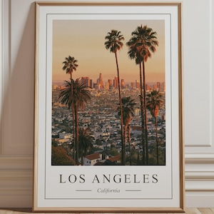 Peut inclure: Une affiche murale verticale encadrée représentant une vue du coucher de soleil sur les gratte-ciel de Los Angeles avec des palmiers au premier plan. L'impression inclut le texte LOS ANGELES et California en bas dans une fine bordure.