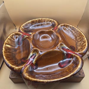 May include: A vintage brown ceramic serving dish with four outer sections and a central bowl. The dish has a glossy finish with red and brown accents. The dish is designed for serving snacks or appetizers.