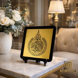 Puede incluir: Taza de cerámica blanca con asa negra y la frase "But First, Coffee" en negro. El fondo borroso sugiere un ambiente acogedor.