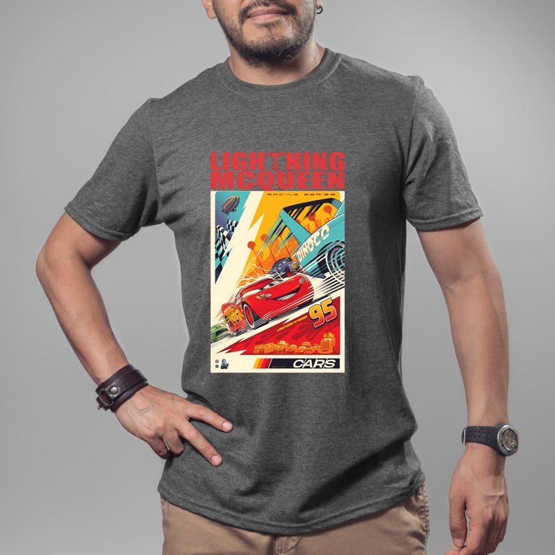 May include: A gray t-shirt featuring a colorful graphic of Lightning McQueen from the movie Cars. The design includes the text "LIGHTNING MCQUEEN" and "CARS", along with the number "95". The graphic has a vintage poster style.