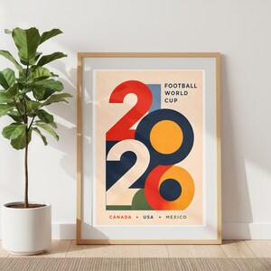 Pu&ograve; includere: Un poster incorniciato con sfondo beige chiaro. Il poster presenta il numero "2026" in forme audaci e colorate: rosso, blu navy, arancione e verde. Il testo "FOOTBALL WORLD CUP" &egrave; sopra i numeri e "CANADA &bull; USA &bull; MEXICO" &egrave; sotto.