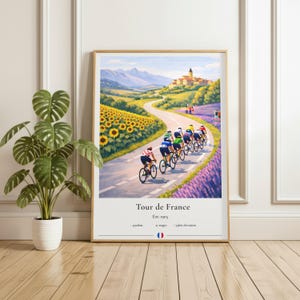 May include: A framed print of the Tour de France, featuring cyclists riding on a winding road through a scenic landscape. The artwork includes sunflowers, lavender fields, and a distant village. The text "Tour de France" and other details are at the bottom.