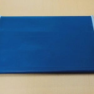 May include: A rectangular, flat, dark blue mat with a smooth, solid-coloured surface. The mat features light grey or silver-toned finished edges along the two shorter sides, providing a clean, structured border to the deep blue central panel.