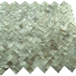 May include: A close-up of a decorative tile mosaic with a herringbone pattern. The tiles are a mix of off-white and iridescent colors, creating a shimmering effect. The mosaic is suitable for wall or floor applications.