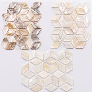 Op de afbeelding: Drie voorbeelden van mozaïektegels met een geometrisch kubusontwerp. De tegels zijn gemaakt van iriserend parelmoer in crème-, beige- en bruintinten. De tegels zijn op een gaasrug gemonteerd.