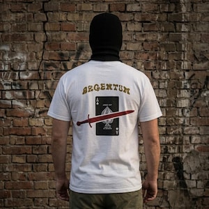 Puede incluir: Una camiseta blanca de manga corta con un gráfico en la espalda. El diseño incluye la palabra ARGENTUM en letras doradas sobre un naipe de as de picas, atravesado horizontalmente por una ilustración de una espada roja.