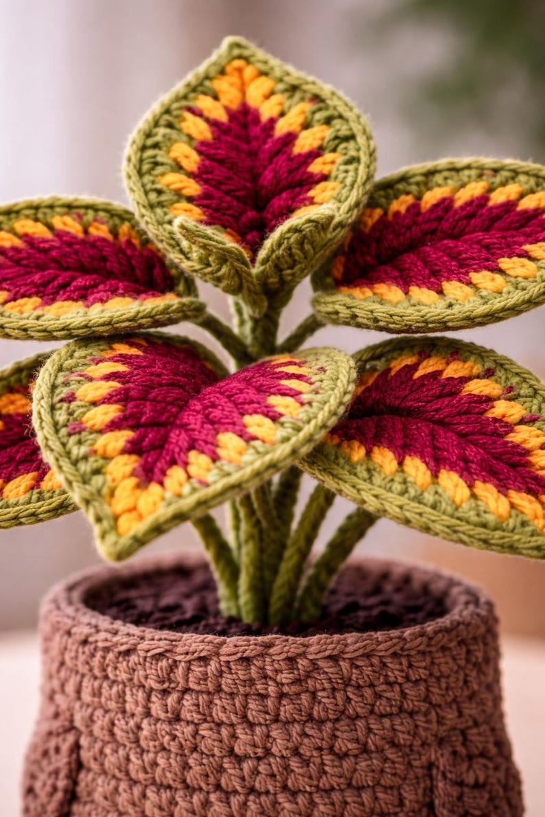 May include: A crocheted plant with green, yellow, and burgundy leaves in a brown crocheted pot. The leaves have a detailed pattern, and the pot has a textured appearance. The plant is a decorative item.