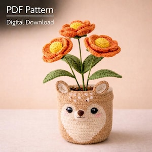 Puede incluir: Una maceta de ganchillo con forma de ciervo, que contiene tres flores de ganchillo naranjas y amarillas con hojas verdes. La maceta es de color beige con una cara blanca y mejillas rosas. El texto en la parte superior dice "PDF Pattern Digital Download."