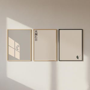 May include: Three framed art prints with minimalist designs. The left print is light grey with a shadow of a plant. The middle print is beige with Japanese text. The right print is beige with a ginkgo leaf. All frames are rectangular.