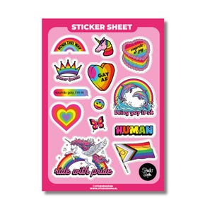Puede incluir: Una hoja de pegatinas rosa con varios diseños que incluyen un arcoíris, un unicornio, un pastel en forma de corazón con texto, una corona, un corazón con texto, una cara sonriente, delfines con arcoíris, una mariposa y una bandera.