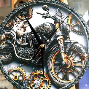 May include: A round wall clock featuring a detailed illustration of a motorcycle surrounded by various metallic gears. The clock face has a dark, textured border with ornate patterns and includes three black hands centered over the motorcycle image.