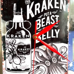 May include: A rectangular wall clock featuring a black and white graphic of a Kraken rum bottle and an octopus. The text reads THE KRAKEN PUT A BEAST IN MY BELLY. The clock has three bright red hands and a gold center pin, with a distressed edge finish.