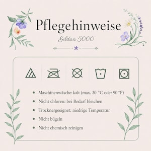 Op de afbeelding: Een onderhoudsinstructiekaart voor een Gildan 5000 kledingstuk met bloemillustraties. Het toont vijf wassymbolen en Duitse tekst voor machinewas op 30 graden Celsius, niet bleken, drogen op lage temperatuur, niet strijken en niet chemisch reinigen.