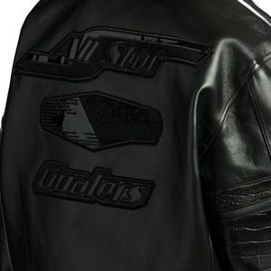 Puede incluir: Chaqueta de cuero negra con parches bordados. Los parches dicen "All Star", un dise&ntilde;o de bandera y "Gualers". La chaqueta tiene un dise&ntilde;o texturizado en las mangas y una raya blanca.