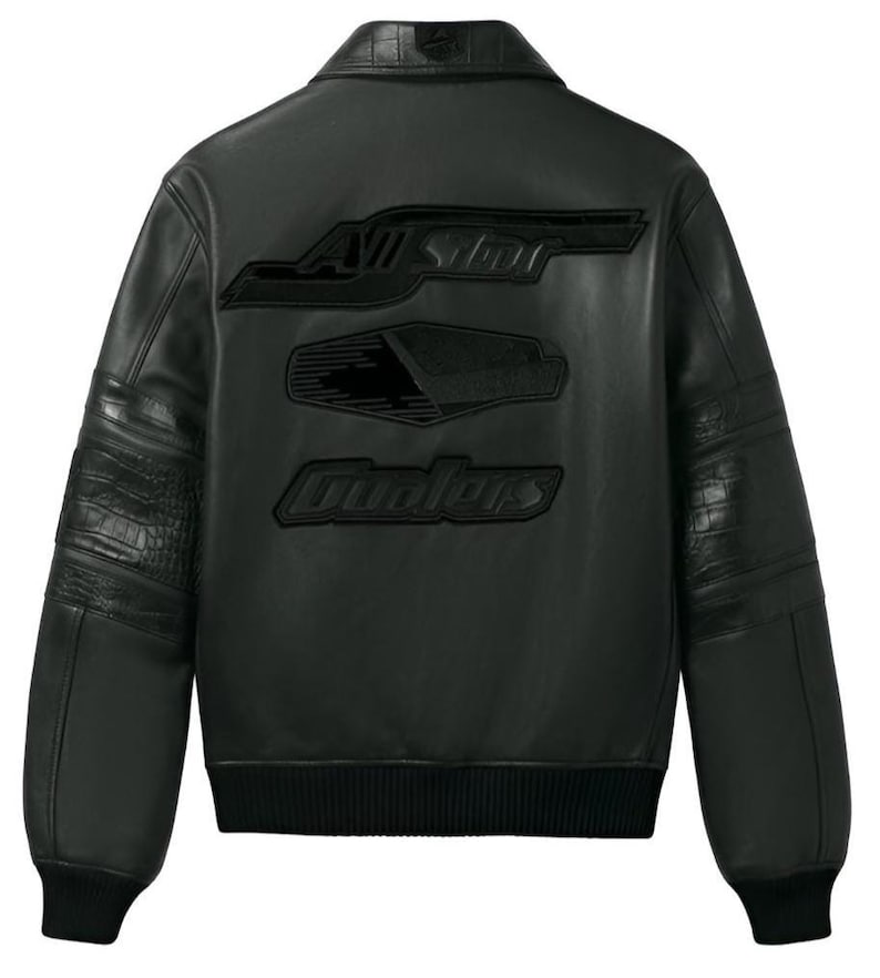 Puede incluir: Chaqueta de cuero negra con pu&ntilde;os y dobladillo acanalados. Presenta texto en relieve en la espalda que dice "All Star" y "Ovolors". La chaqueta tiene un estilo bomber cl&aacute;sico con cuello y paneles texturizados en las mangas.