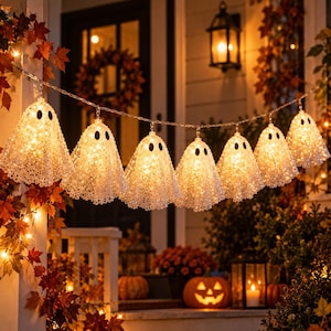 Puede incluir: Una guirnalda de ocho decoraciones iluminadas con forma de fantasma colgadas en fila. Cada fantasma está hecho de un material blanco, texturizado y semitransparente con dos ojos ovalados negros, y contiene luces blancas cálidas en su interior.