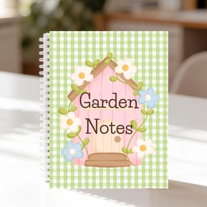 以下が含まれることがあります： ピンクの家のデザインと「Garden Notes」の文字が入ったスパイラル綴じノート。表紙は緑と白のギンガムチェック柄。家は白と青の花と緑のつるで飾られています。