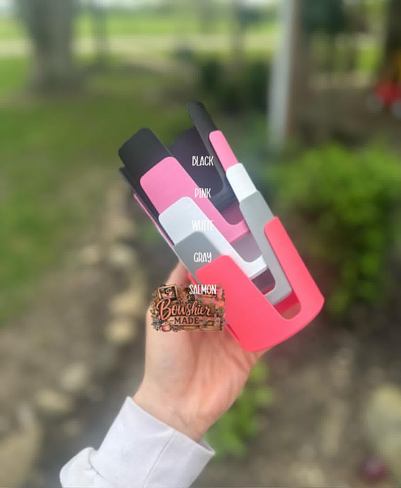 Puede incluir: Una colecci&oacute;n de fundas de tel&eacute;fono coloridas en negro, rosa, blanco, gris y salm&oacute;n. Las fundas se sostienen en una mano y est&aacute;n etiquetadas con sus respectivos colores. La marca "Bowshier Made" tambi&eacute;n es visible.