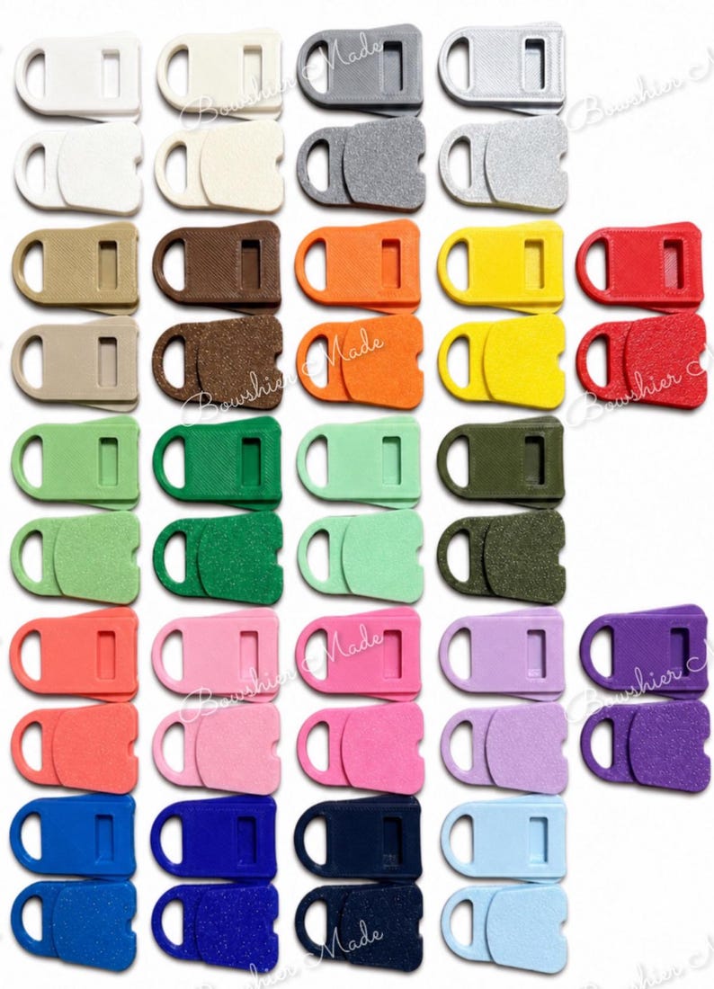 May include: A collection of colorful plastic buckle clasps in various shades, including white, gray, brown, orange, yellow, red, green, pink, purple, and blue. Each clasp features a rectangular body with a loop and a slot.