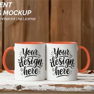 Könnte beinhalten: Zwei weiße Akzent-Tassen mit orangefarbenen Innenräumen und Griffen. Jede Tasse trägt den schwarzen Schriftzug "Your design here". Das Bild enthält den Text "ACCENT MUG MOCKUP With Commercial Use License".