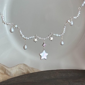 Op de afbeelding: Een witte keramische mok met een zwarte handgreep en de tekst "But First, Coffee" in een vetgedrukte, zwarte letter. De mok staat tegen een wazige achtergrond, wat een gezellige setting suggereert.