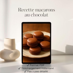 Peut inclure: Un écran affiche une assiette de macarons au chocolat. Le texte "Recette macarons au chocolat" est visible. En dessous, trois coches avec du texte français. Un vase beige est à gauche.