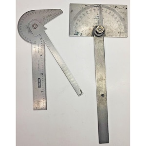 Puede incluir: Dos transportadores de metal vintage. Uno tiene una regla con medidas en pulgadas, el otro tiene una base rectangular. Ambos son de color plateado con marcas de grados. La regla está marcada "GENERAL" y "STAINLESS STEEL".