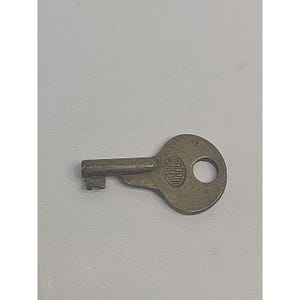 May include: A vintage brass key with a circular head and a keyhole. The key has a rectangular key bit and the word "CORBIN" is stamped on the head. The key is set against a plain white background.