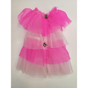 May include: A doll-sized pink and white dress with a layered skirt and ruffled sleeves. The dress features two decorative buttons down the front and is made of sheer fabric.