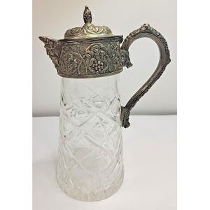 May include: A white ceramic mug with a black handle and the text "But First, Coffee" in a black, bold font. The mug is on a white surface.