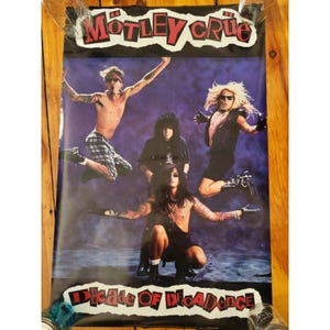 Puede incluir: Un póster de la banda Mötley Crüe con el texto "Mötley Crüe" en la parte superior y "Decade of Decadence" en la parte inferior. Los miembros de la banda se muestran en varias poses sobre un fondo púrpura.