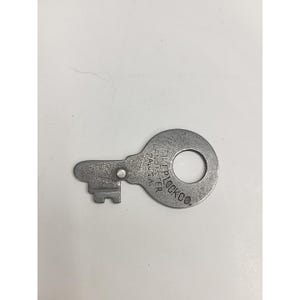 Puede incluir: Una llave vintage de color plateado con una cabeza circular y un ojo de cerradura. La llave tiene una paleta rectangular con un patrón dentado. La cabeza de la llave está estampada con el texto "Yale & Towne, Lancaster, PA, U.S.A., LOCK CO."