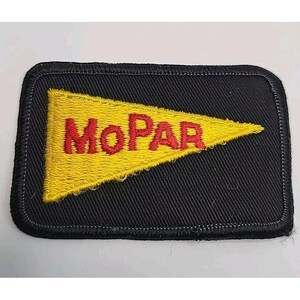 May include: A rectangular black embroidered patch featuring a yellow pennant-shaped design in the centre. The word MOPAR is stitched in red capital letters across the yellow pennant. The patch has a thick black stitched border around the edge.