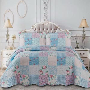 May include: A patchwork quilt set in shades of blue, pink, and white, with floral and checkered patterns. The set includes a quilt and two pillow shams. The quilt is displayed on a bed with a decorative headboard and matching bedside tables.