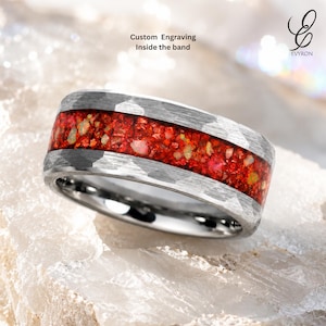 Puede incluir: Un anillo plateado con acabado martillado y una incrustación central de material rojo triturado con motas iridiscentes. El texto Custom Engraving Inside the band es visible arriba y el logotipo EVYRON está en la esquina superior derecha.
