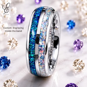 Peut inclure: Une bague argentée dotée de deux canaux incrustés distincts. L'un contient des éclats de matériau bleu profond, tandis que l'autre présente des éclats iridescents multicolores. Le texte Custom Engraving Inside the band est visible.