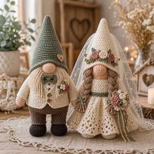 May include: Two crocheted gnome figures dressed for a wedding. The left gnome wears a green pointed hat, a cream vest, and brown trousers. The right gnome wears a cream dress, a matching hat with floral accents, and a sheer white veil.